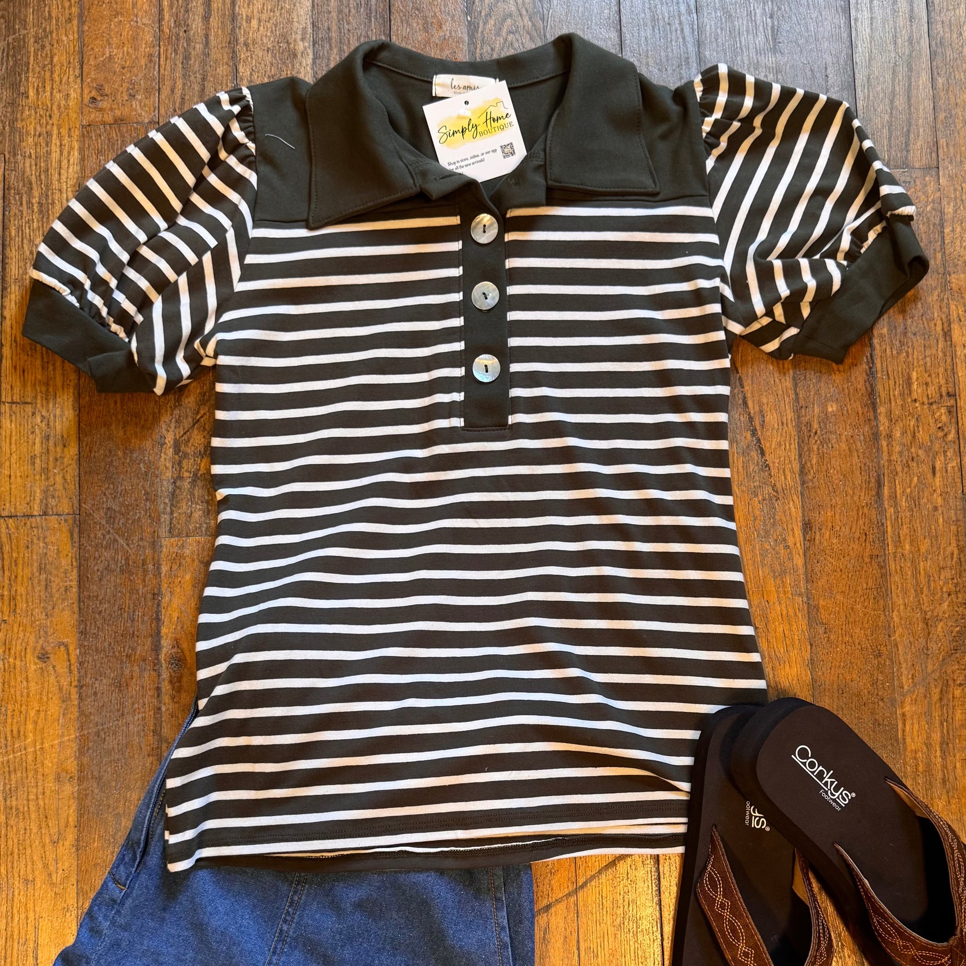 Striped shirt, blue shorts, and sandals on a wooden floor