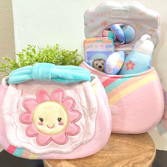 Pink baby purse with a flower design and colorful toys in the background.