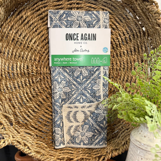 Packaged towel with floral design and 'Once Again Home Co' branding on a woven surface.