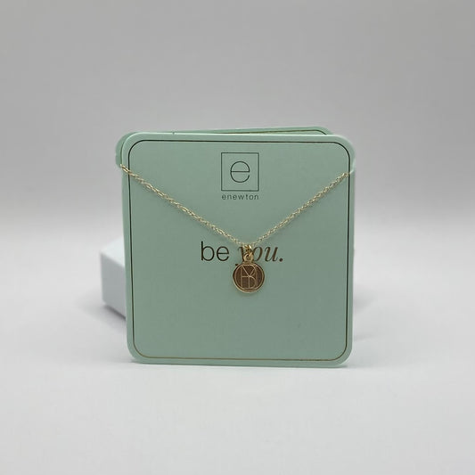 Gold necklace with a pendant on a green box labeled 'be you.'