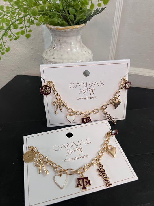 Two gold charm bracelets on Canvas brand cards with a plant in the background.