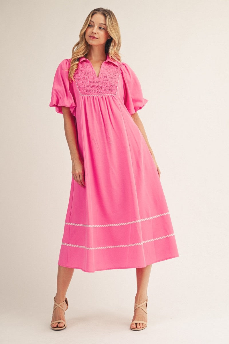 Woman wearing a pink dress with white trim on a beige background