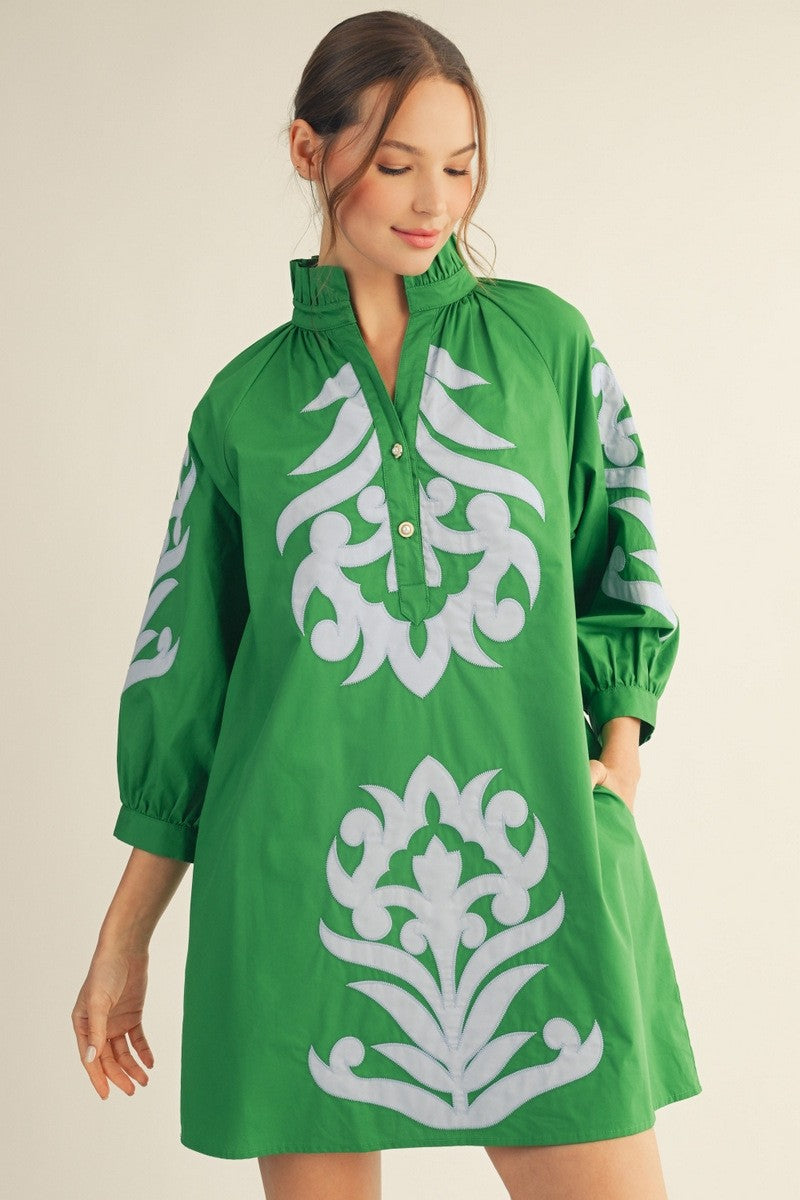 Woman wearing a green dress with white floral patterns on a beige background