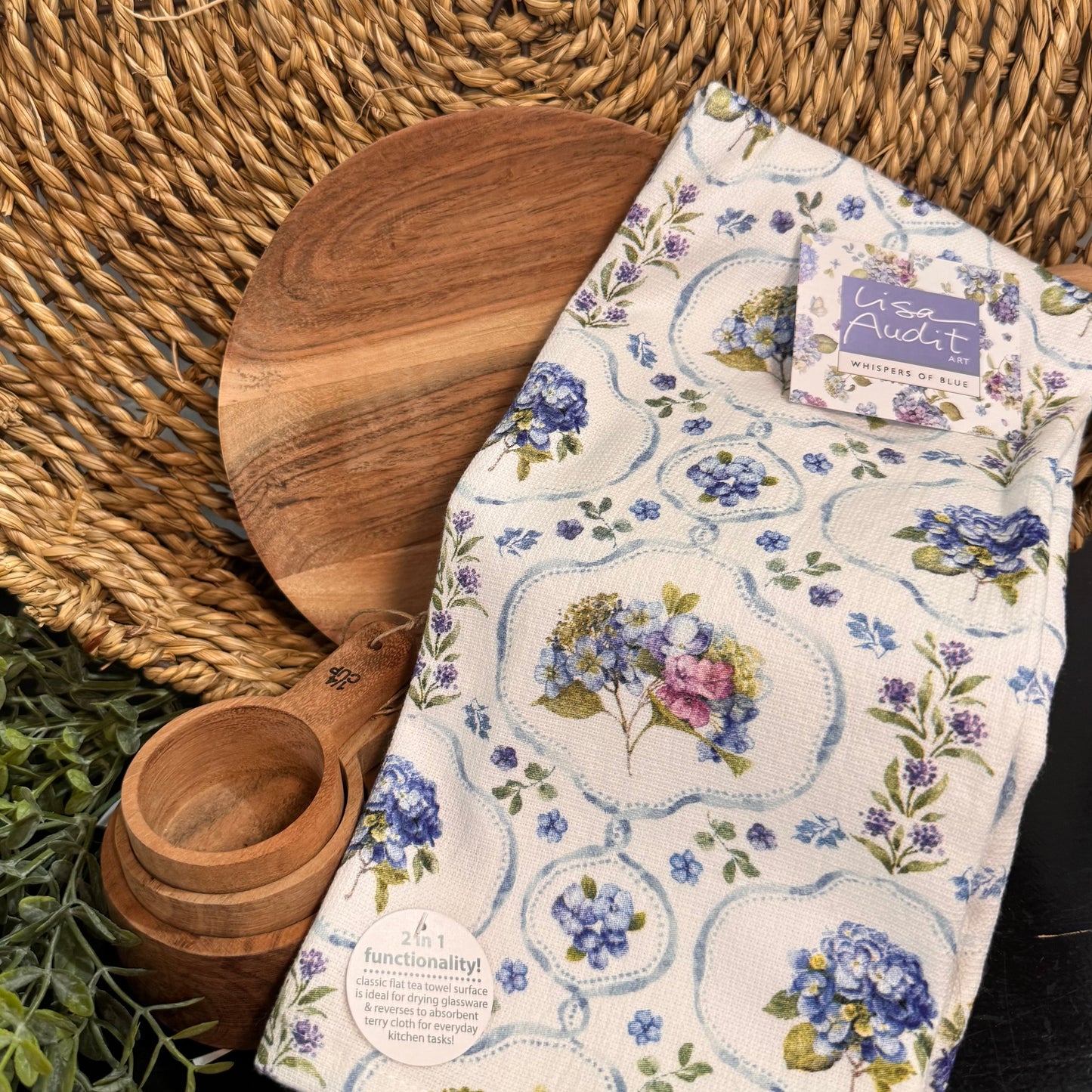 Wooden cutting board and measuring cup with a floral towel on a woven mat