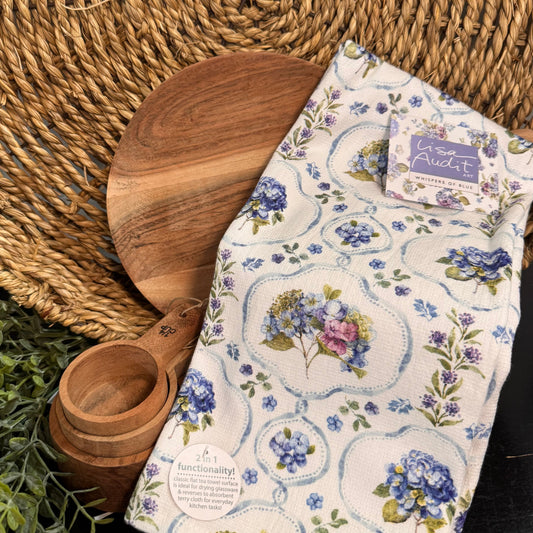 Wooden cutting board and measuring cup with a floral towel on a woven mat