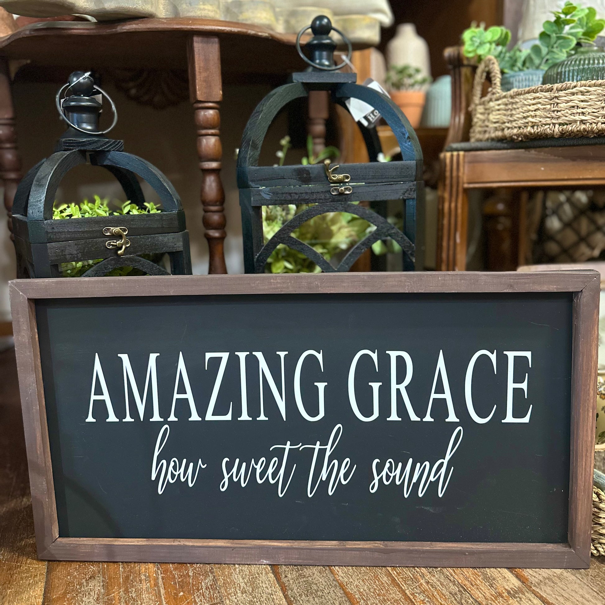 Decorative sign with 'Amazing Grace, how sweet the sound' text in a home setting with lanterns and plants.