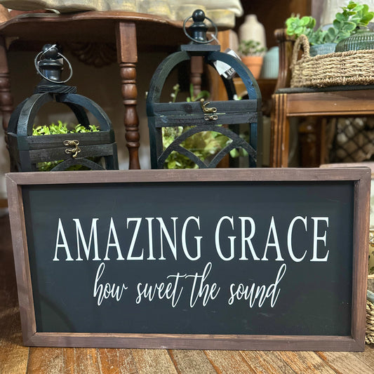 Decorative sign with 'Amazing Grace, how sweet the sound' text in a home setting with lanterns and plants.