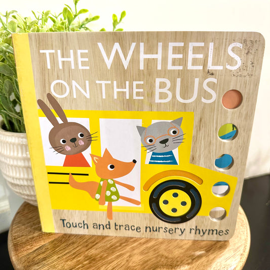 Children's book titled 'The Wheels on the Bus' with animal illustrations on a wooden stand.