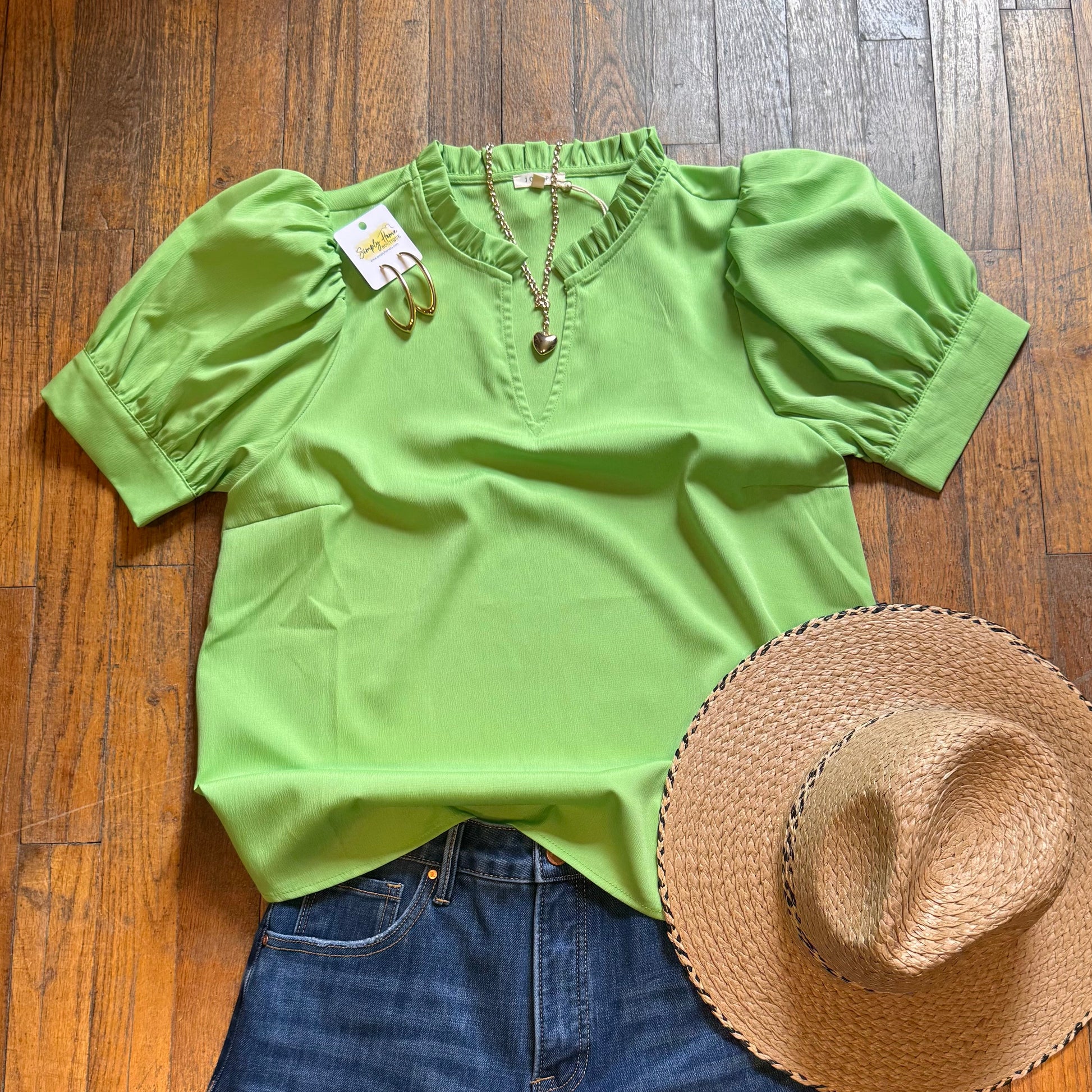 Green blouse, blue jeans, and straw hat on a wooden floor