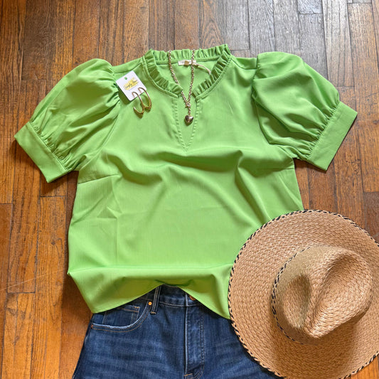 Green blouse, blue jeans, and straw hat on a wooden floor
