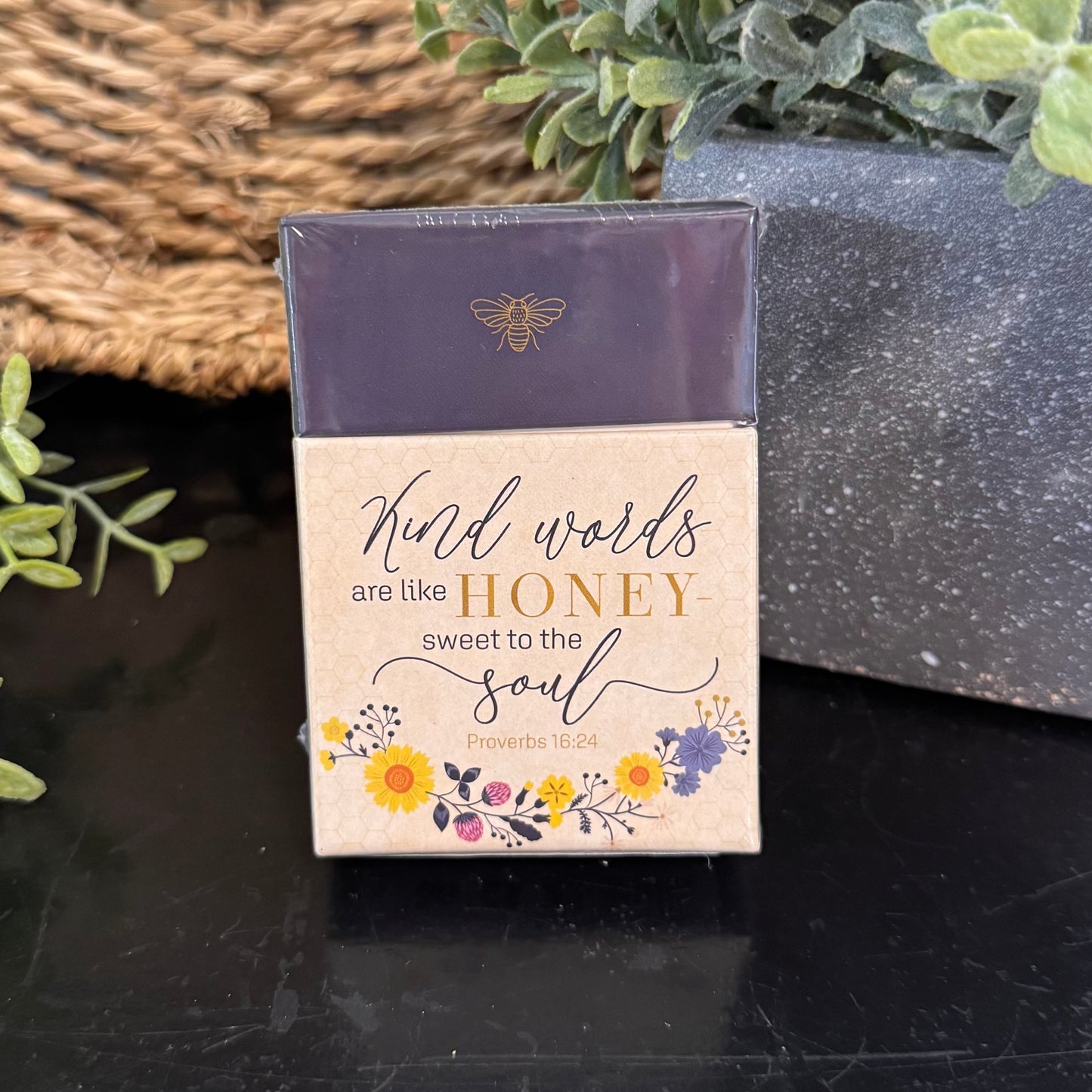 Small box with motivational quote on a dark surface with plants in the background