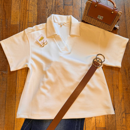 White polo shirt with a brown strap on a wooden floor