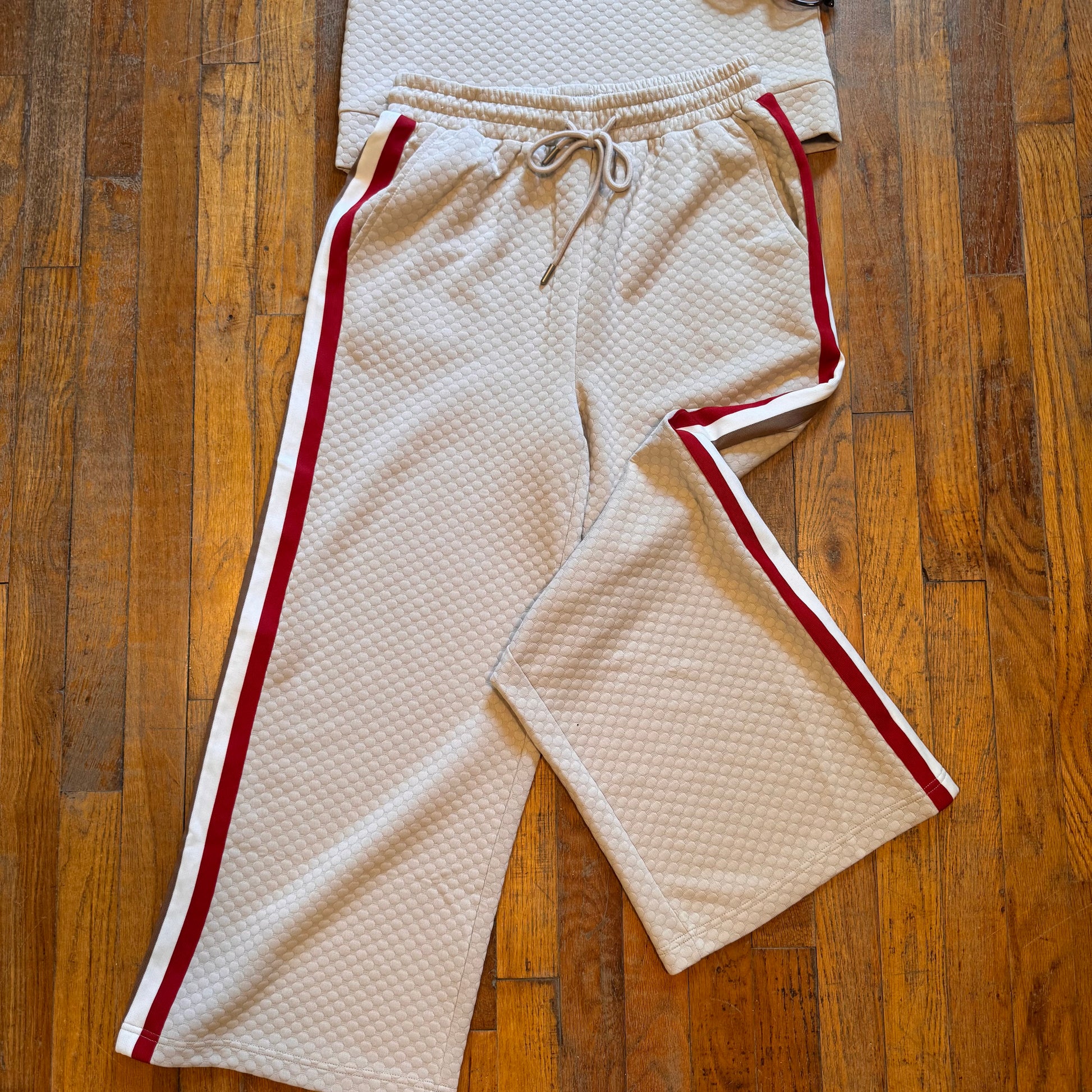 Beige tracksuit with red accents on a wooden floor