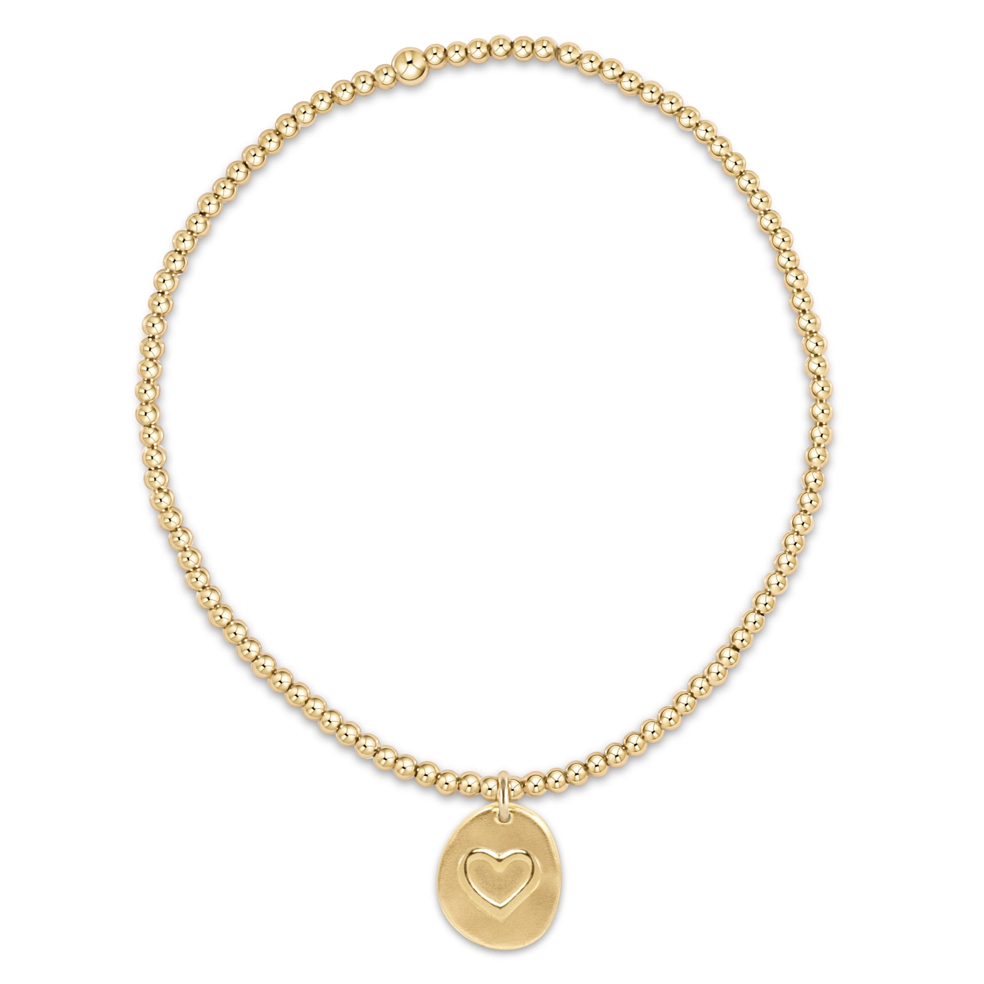 Gold bracelet with a heart-shaped charm on a white background