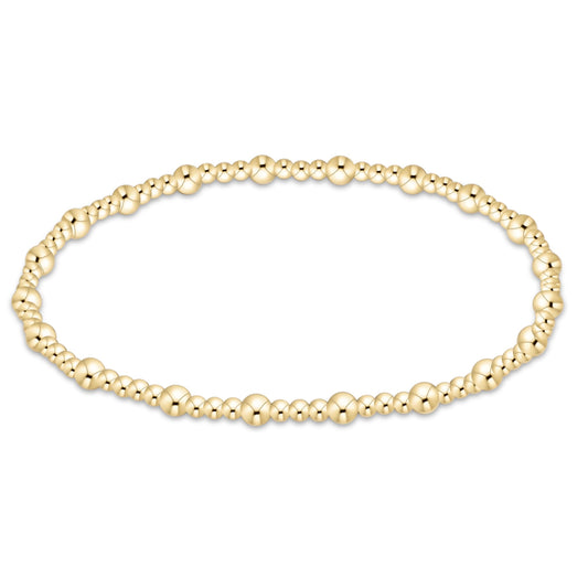 A gold beaded stretch bracelet with alternating large and small polished round beads, displayed in a horizontal oval shape on a clean white background.