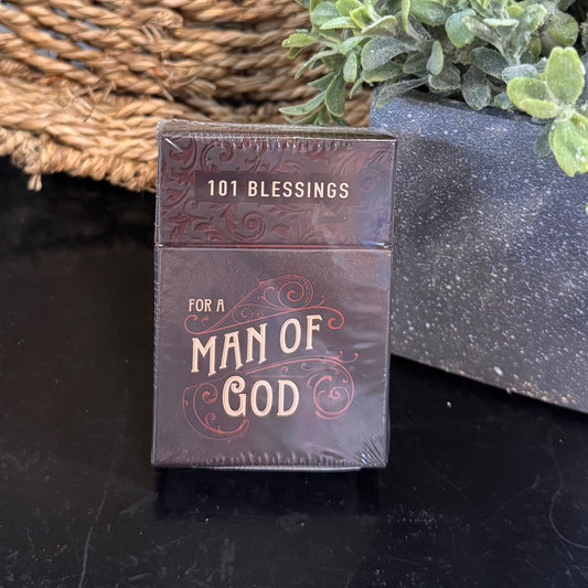 Small book titled '101 Blessings for a Man of God' next to a potted plant on a dark surface.