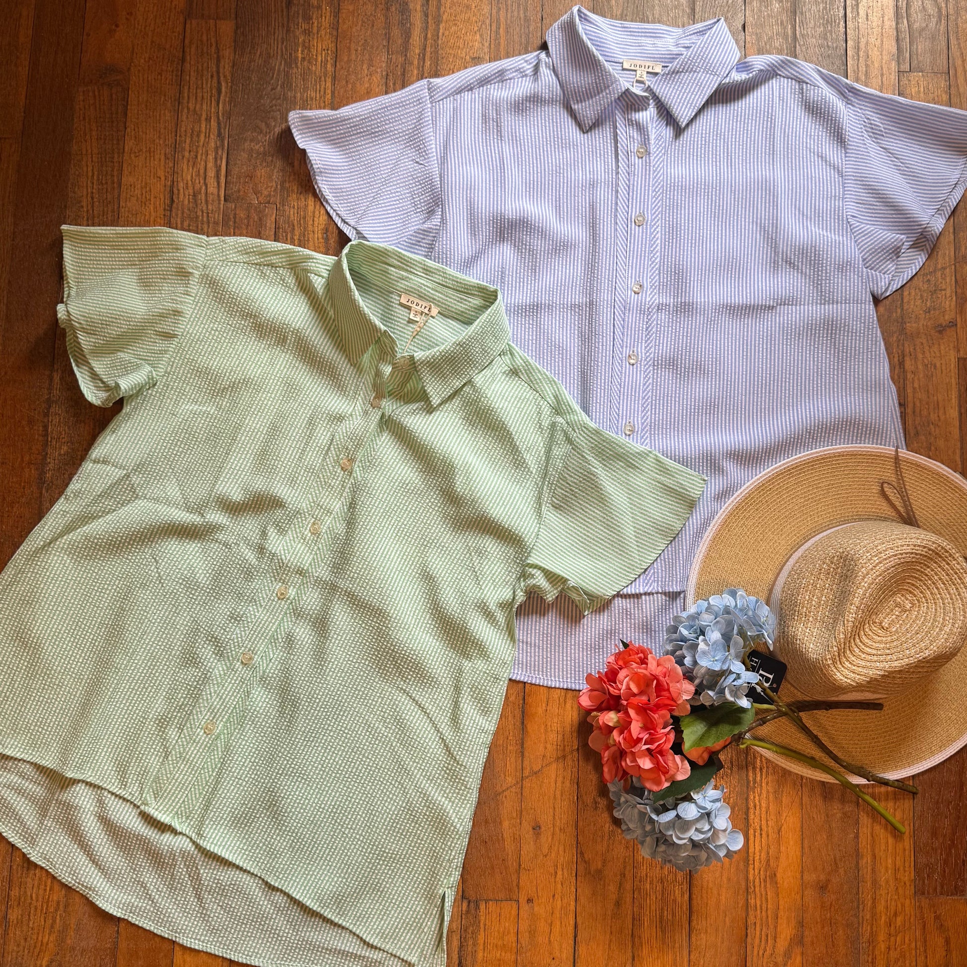 Two shirts and a hat on a wooden floor with flowers.