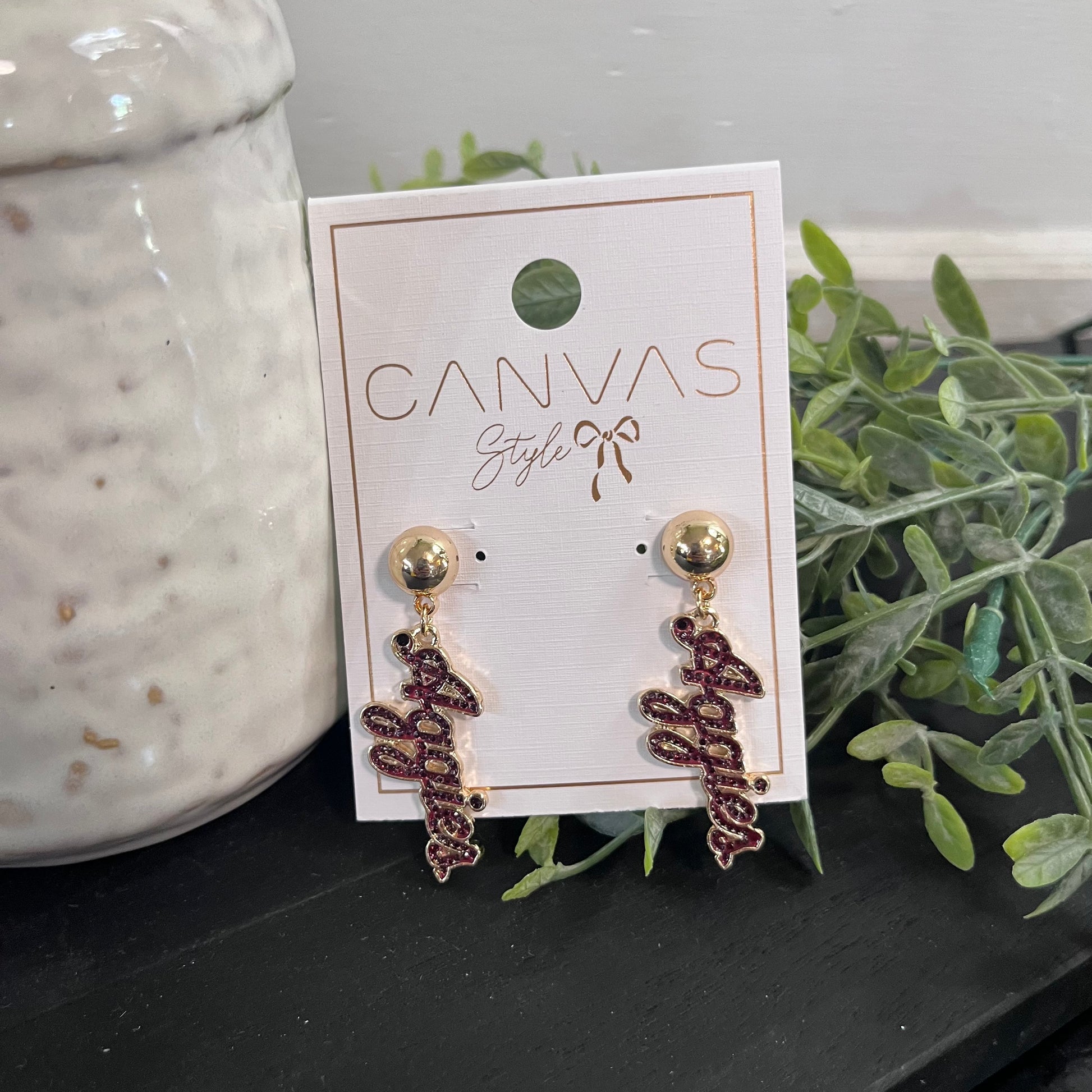 Pair of earrings on a 'Canvas Style' branded card with a plant and ceramic item in the background.