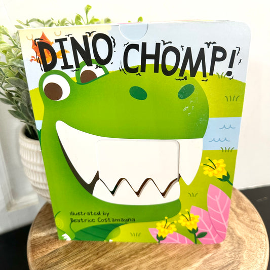 Children's book titled 'Dino Chomp' with a dinosaur illustration on a wooden surface.