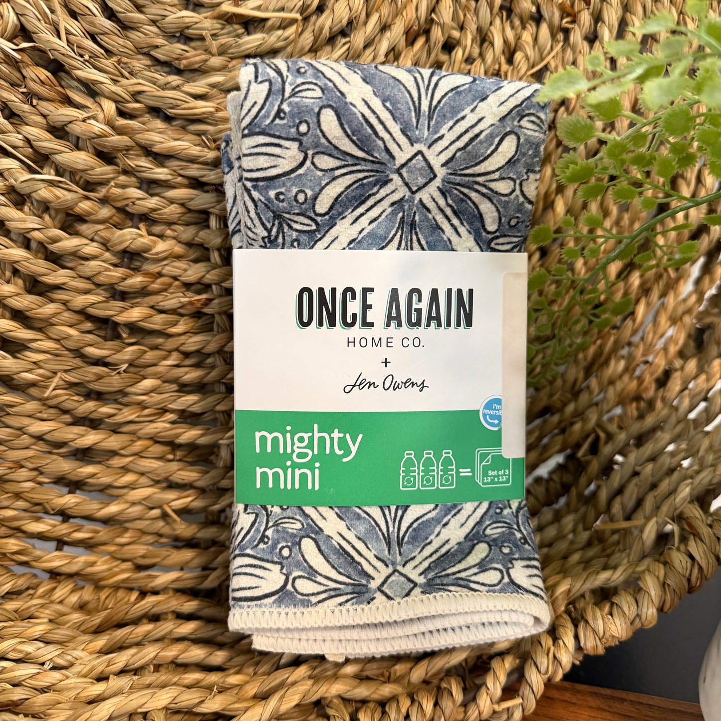 Folded fabric with 'Once Again Home Co.' packaging on a woven surface