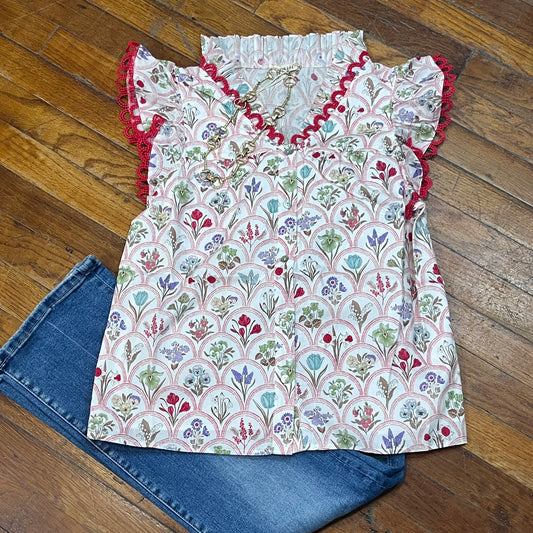 Floral patterned top with red trim on a wooden floor