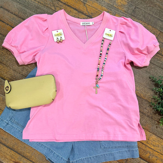 Pink top with denim shorts and a yellow purse on a wooden surface