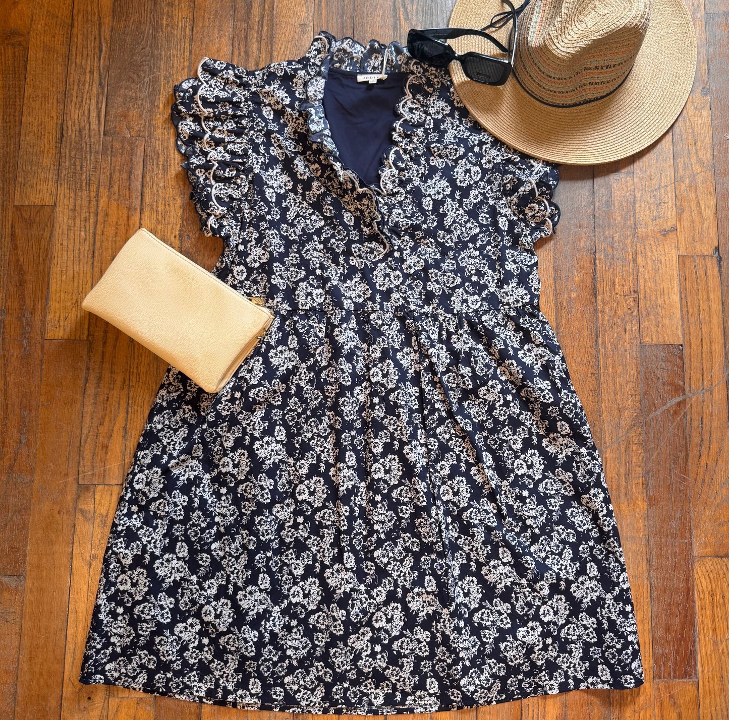 Floral dress with a hat and clutch on a wooden floor