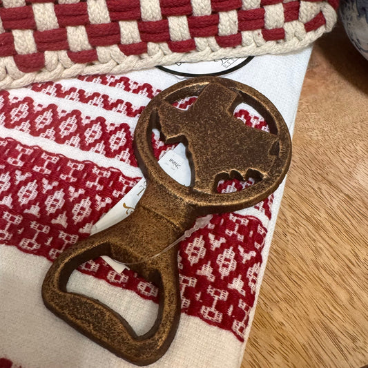Bronze bottle opener with bear design on a red and white checkered towel