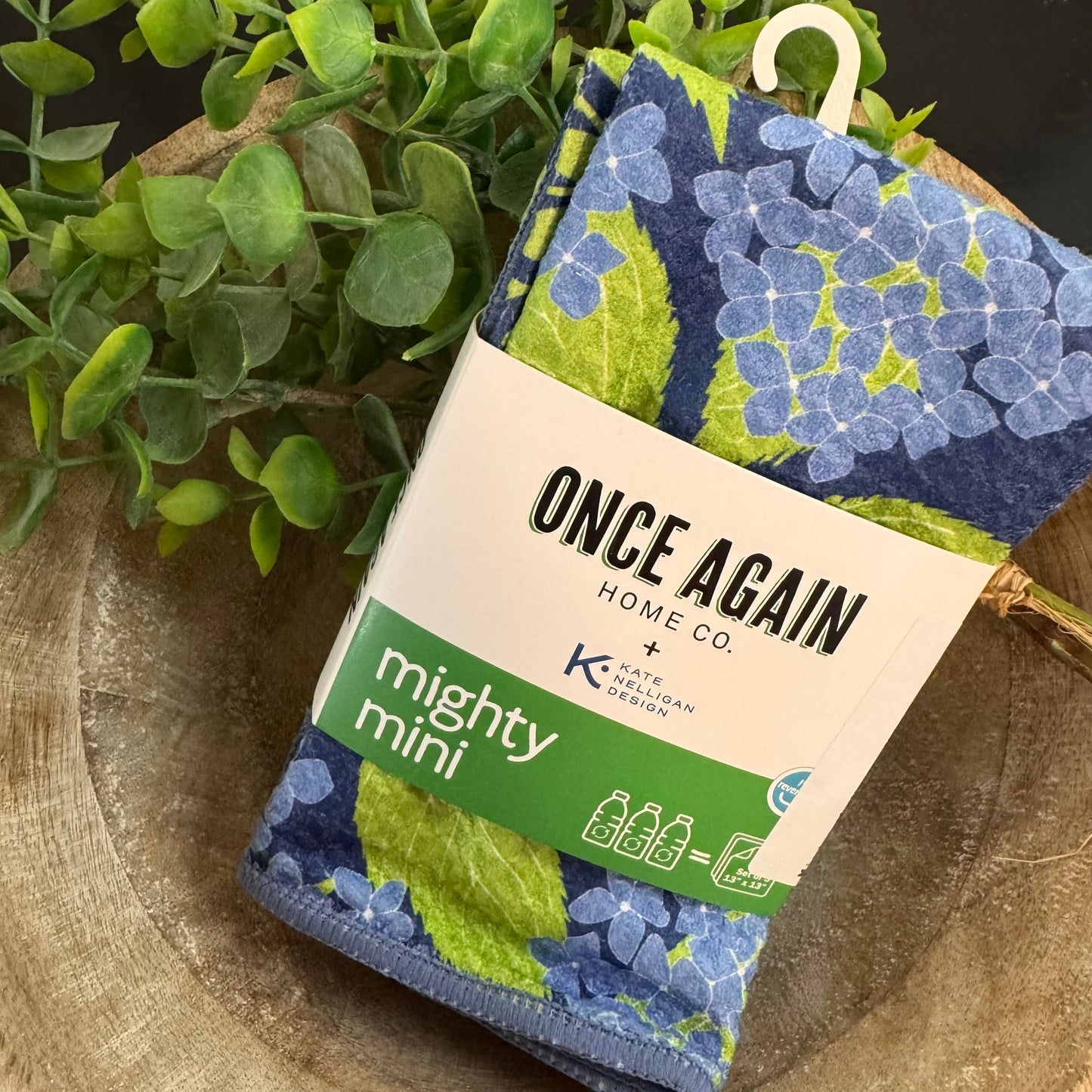Packaged product with floral design and 'Once Again Home Co' branding on a wooden surface with greenery.