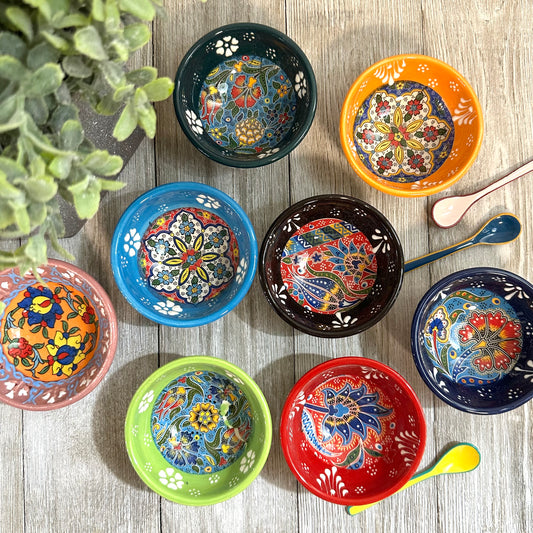 Colorful ceramic bowls with floral patterns on a wooden surface.
