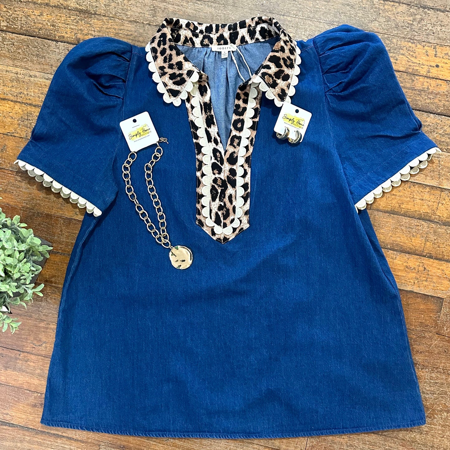 Blue dress with leopard print collar and ruffled sleeves on a wooden surface