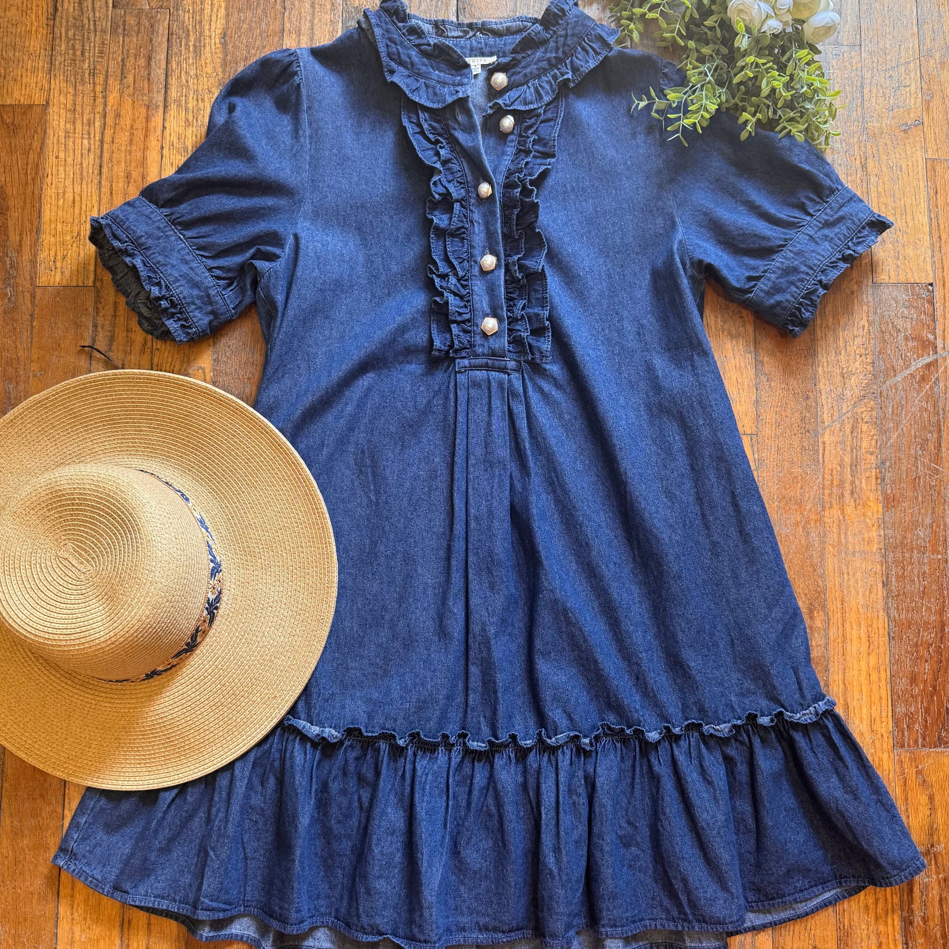 Blue off-shoulder top with ruffled details and a straw hat on a wooden surface.