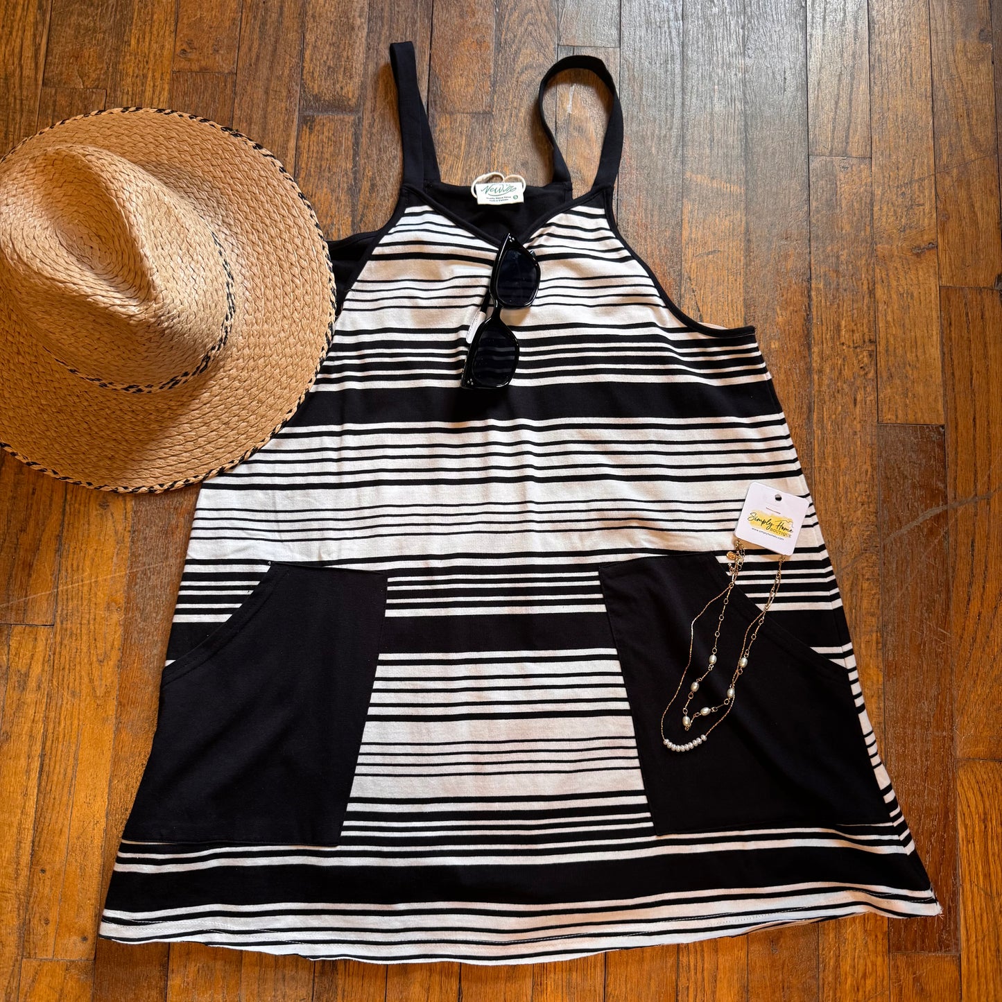 Black and white striped dress with a straw hat on a wooden floor