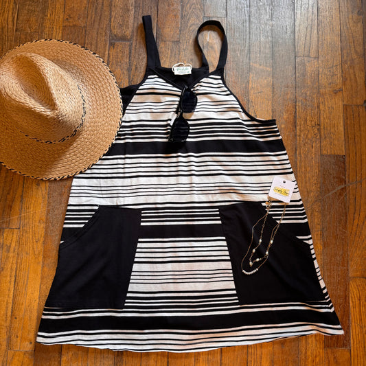 Black and white striped dress with a straw hat on a wooden floor
