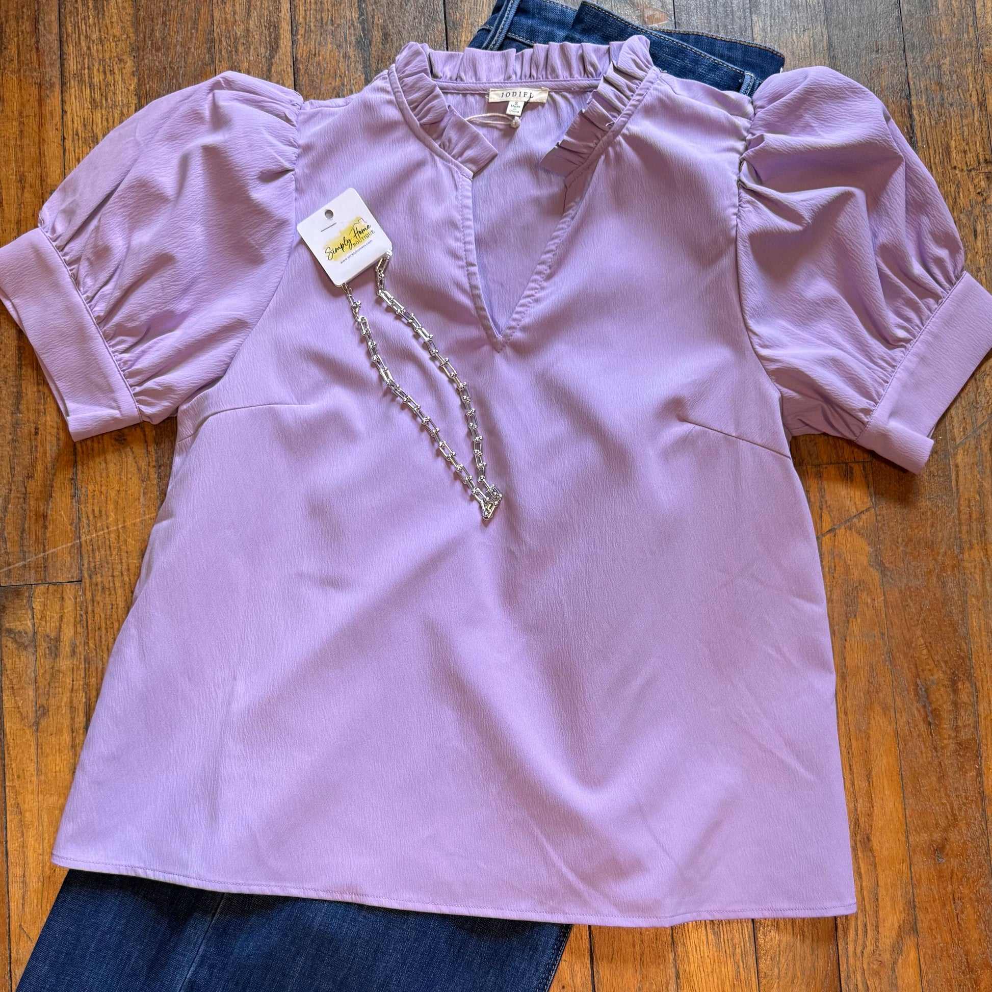 Purple blouse with a tag on a wooden floor