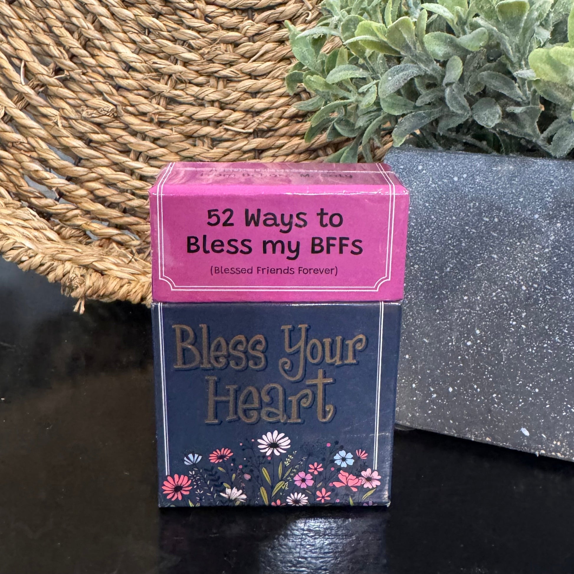 Card game box titled 'Bless Your Heart' with a pink lid on a dark surface.