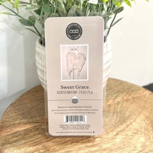 Scented wax bar packaging labeled 'Sweet Grace' on a wooden surface with a plant in the background.