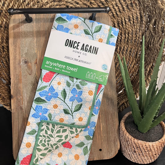 Floral towel packaging with 'Once Again Home Co' branding on a wooden surface with a plant.
